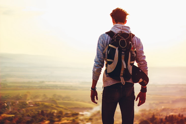 Man with bagpack on mountain top, illustrating depression challenges in Denver.