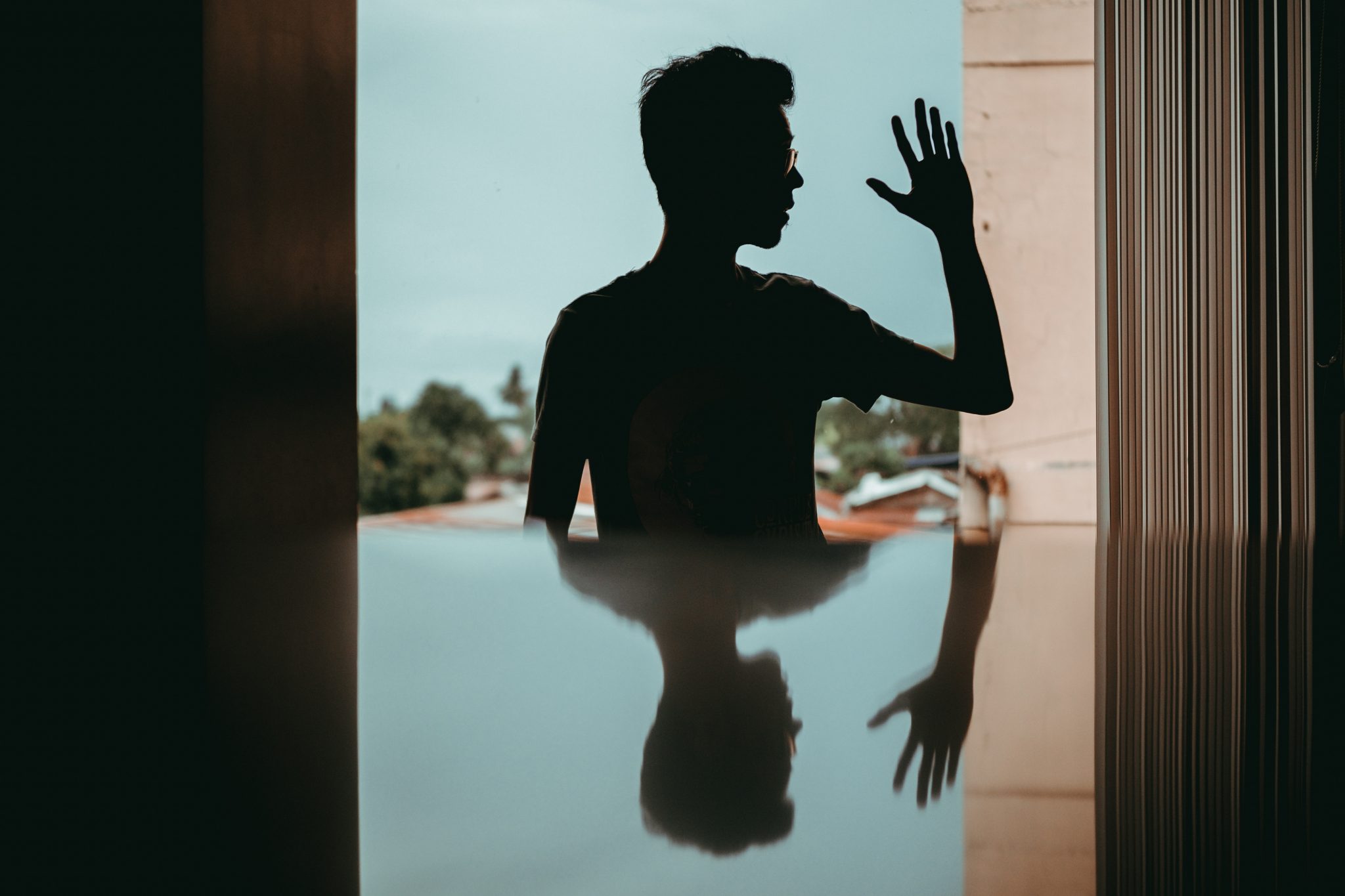 Man raising his hand and looking at his reflection signifying the unique mental health needs of men