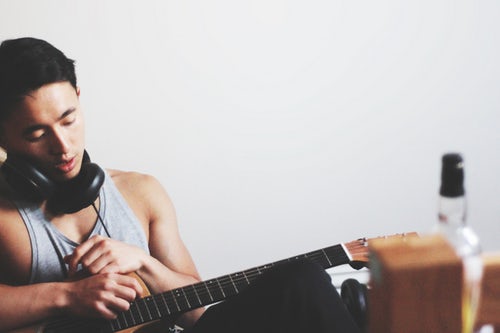 Man playing guitar with alcohol in room, symbolizing substance abuse issues