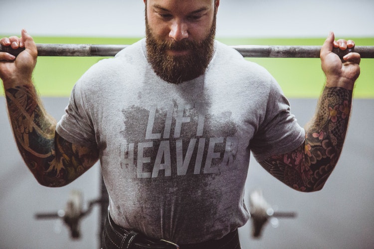 Man lifting weights, highlighting body image issues and therapy needs.