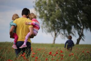 Father and children in poppy field, depicting fatherhood joys and therapy support.