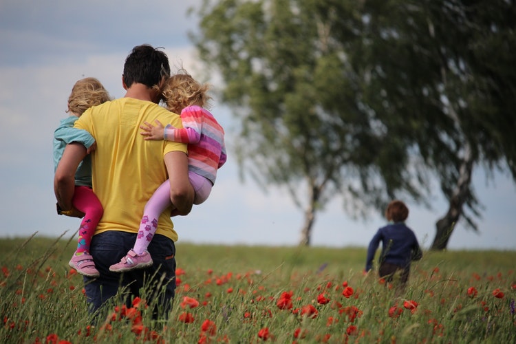 Father and children in poppy field, depicting fatherhood joys and therapy support.