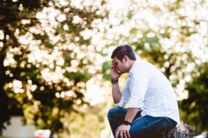 A man sitting upset in a garden considering to take therapy for the first time