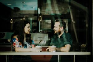 Couple sitting face to face discussing mental health, promoting open therapy dialogue.