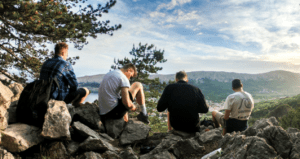 Men on hilltop enjoying emphasizing self-care practices.