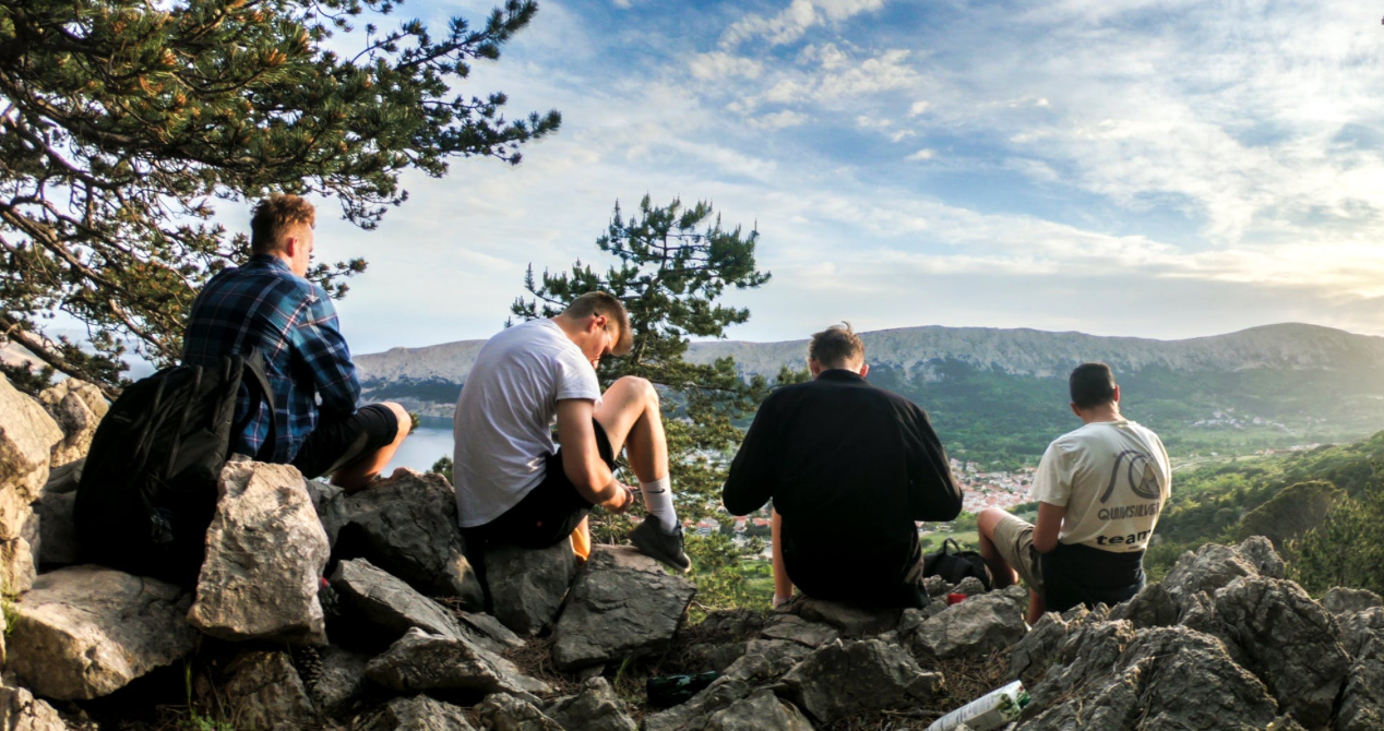 Men on hilltop enjoying emphasizing self-care practices.