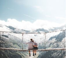 Couples sitting on a bridge between the mountains portraying couples counseling in denver