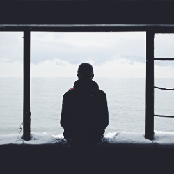 Man looking into the vast nothingness of the sea dealing with trauma and emotional distress