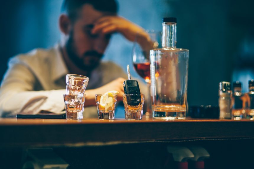 Man sitting upset at a bar and coping up with drinks