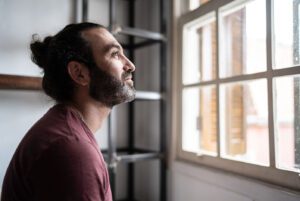 Man smiling and looking outside window thinking about therapy.