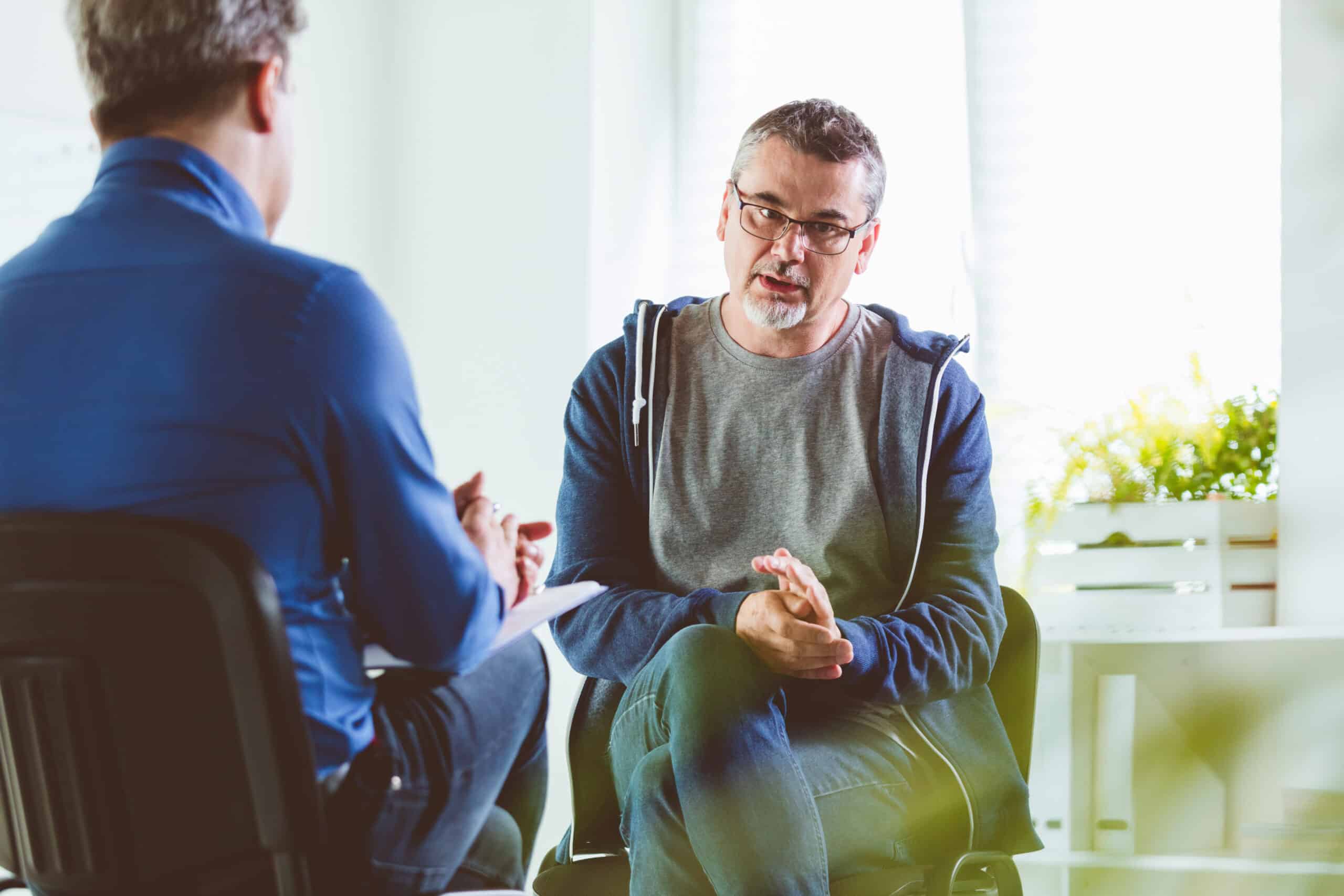 Man in therapeutic dialogue with therapist, promoting open therapy communication.