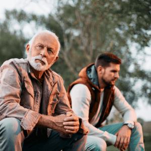 Father and son outdoors, facing away from each other with sadness