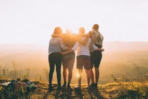 Friends huddle together, watching the sunrise paint the sky