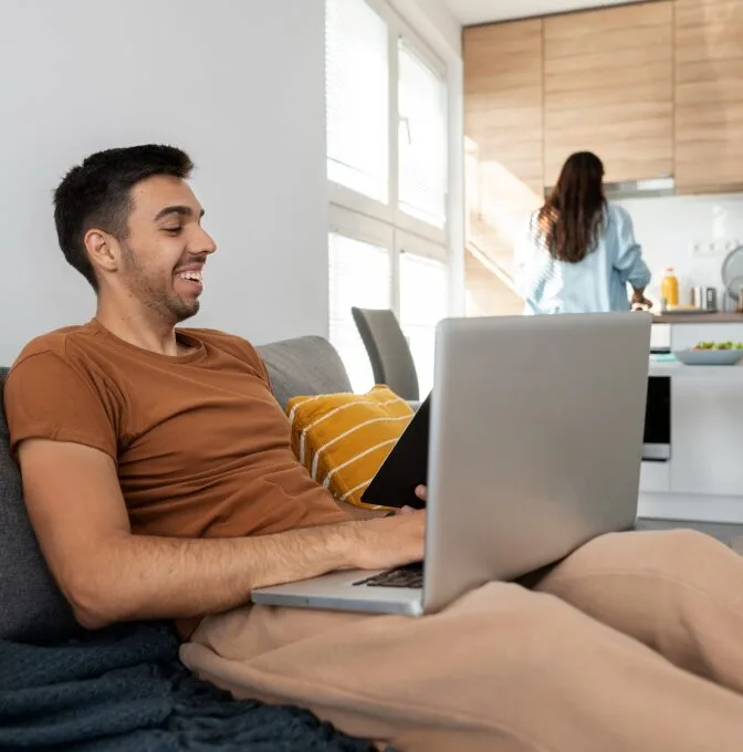 Man sitting on his sofa, smiling at the screen, feeling supported with Colorado teletherapy services