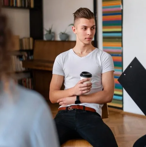 Man sipping coffee while receiving advice from an LGBTQ therapist in Denver.