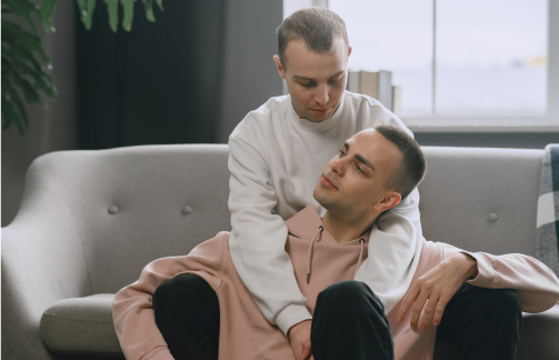 A man hugging his male partner from behind, affirming their decision to take therapy for gay men