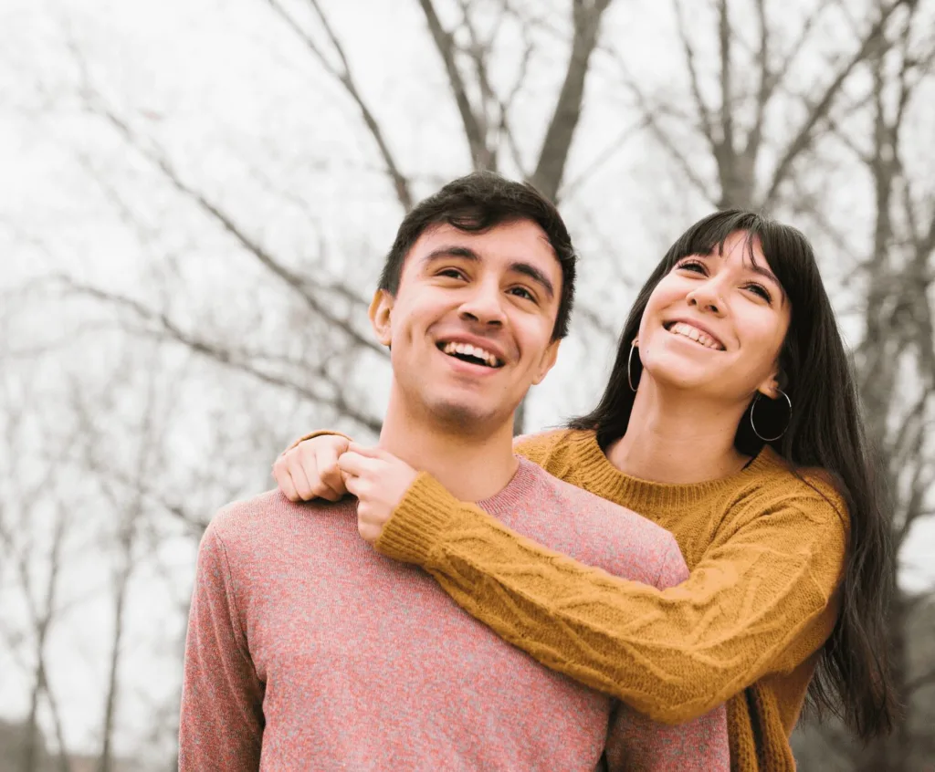 A woman hugging her partner from behind, representing the emotional support provided in sex therapy.