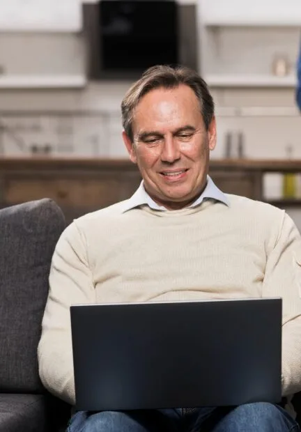 Middle-aged man scheduling an online therapy session in Denver, Colorado from his laptop at home.