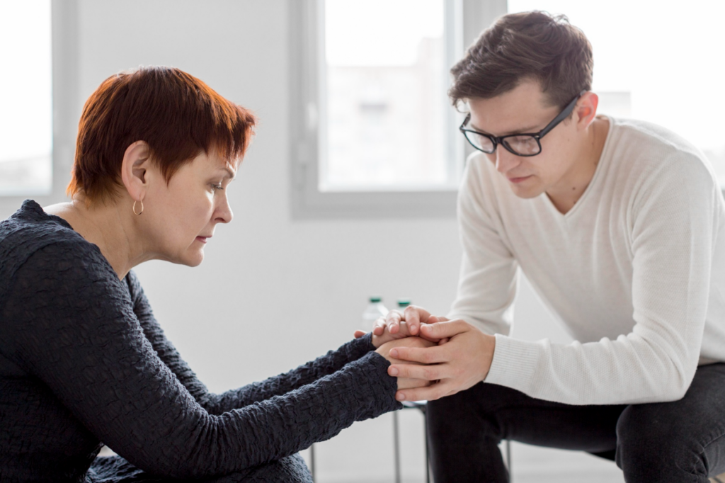 Man sitting & gently holding partner's hands in his palms processing grief via counseling in Denver