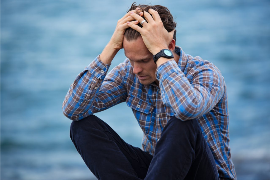 A distressed man holding his head, reflecting the need for grief therapy in Denver