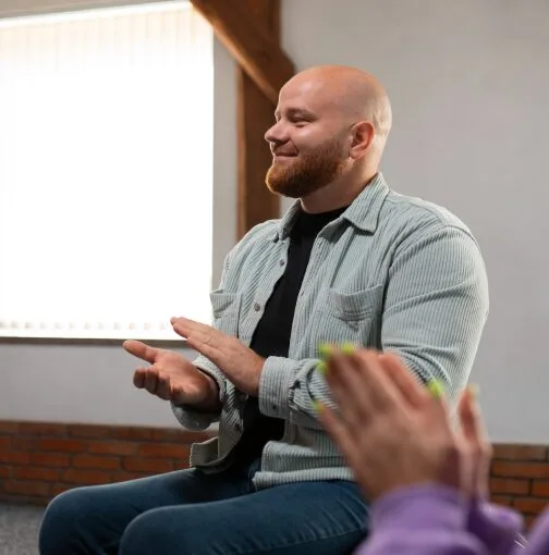 A man applauding a fellow member during a group therapy session in Denver.