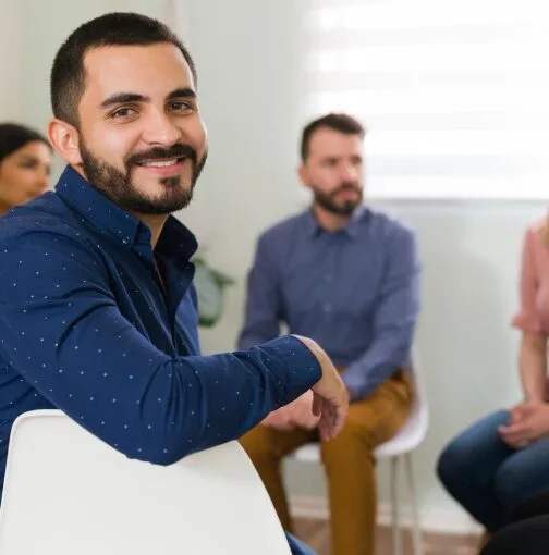 A man smiling warmly, promoting the benefits of group therapy for men.