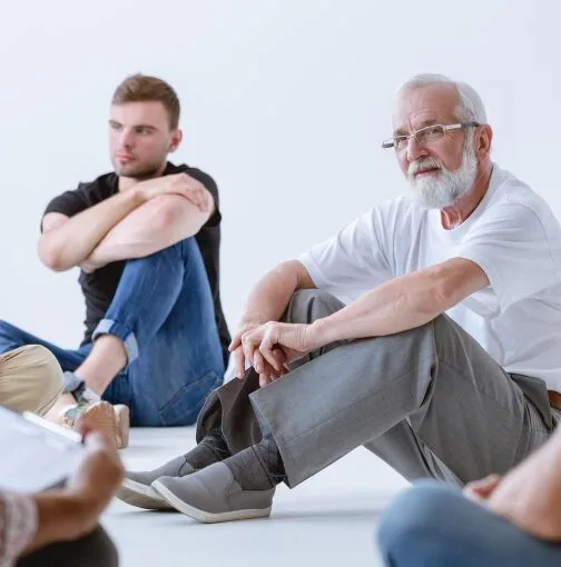 An elderly man participating in a group therapy session in Denver.