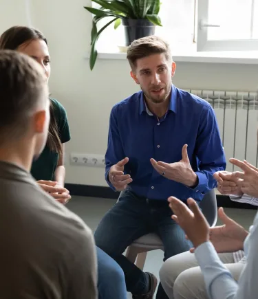 A man sharing his struggles during a group therapy session in Denver.