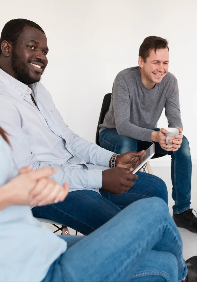 Men smiling and feeling relieved after openly sharing their concerns in group therapy.