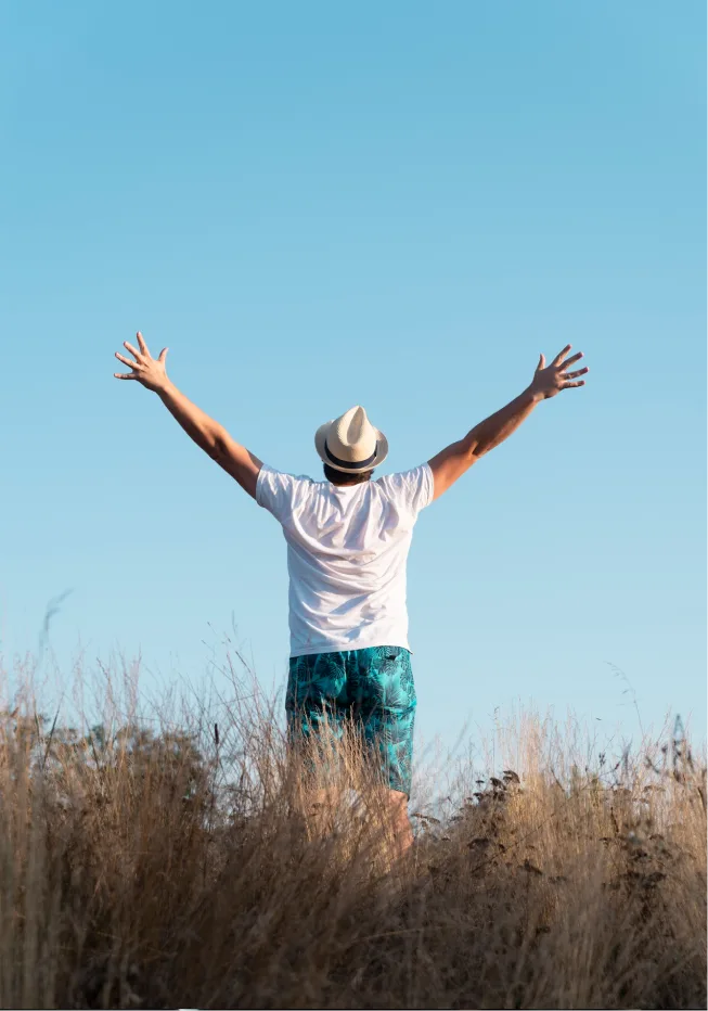 Man facing a large open field with open arms feeling joyful after PTSD treatment in Denver.