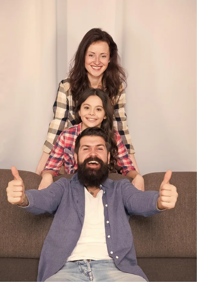 Man posing for a fun family photograph with his wife and daughter after successful PTSD treatment.