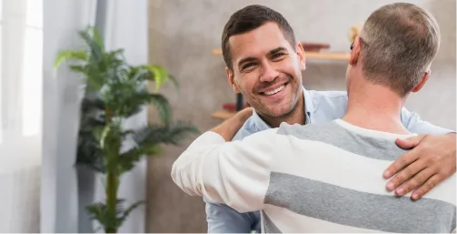 Man hugging his therapist happily after recovering from PTSD through trauma therapy in Denver.