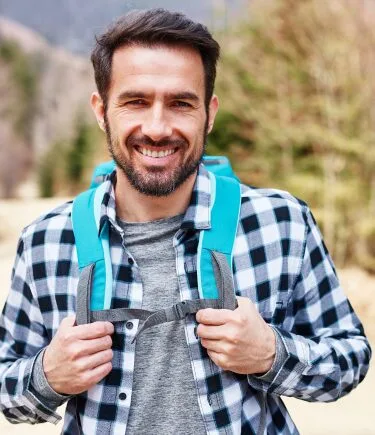 A traveler smiling and enjoying his hike post a PTSD therapy session in Denver with a compassionate trauma therapist.