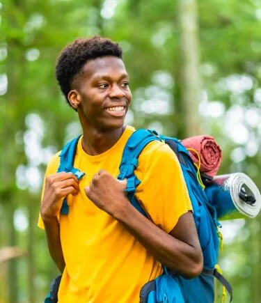 Smiling young man holding a yoga mat, leading a healthy lifestyle after teen therapy in Denver