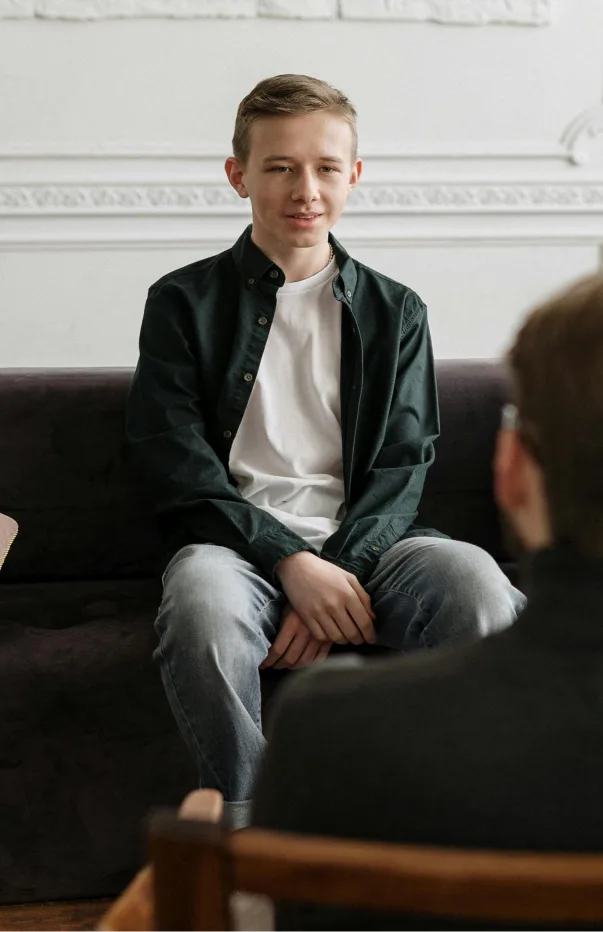 A young shy teen sharing his concerns with a therapist during a counseling session in Denver, CO.