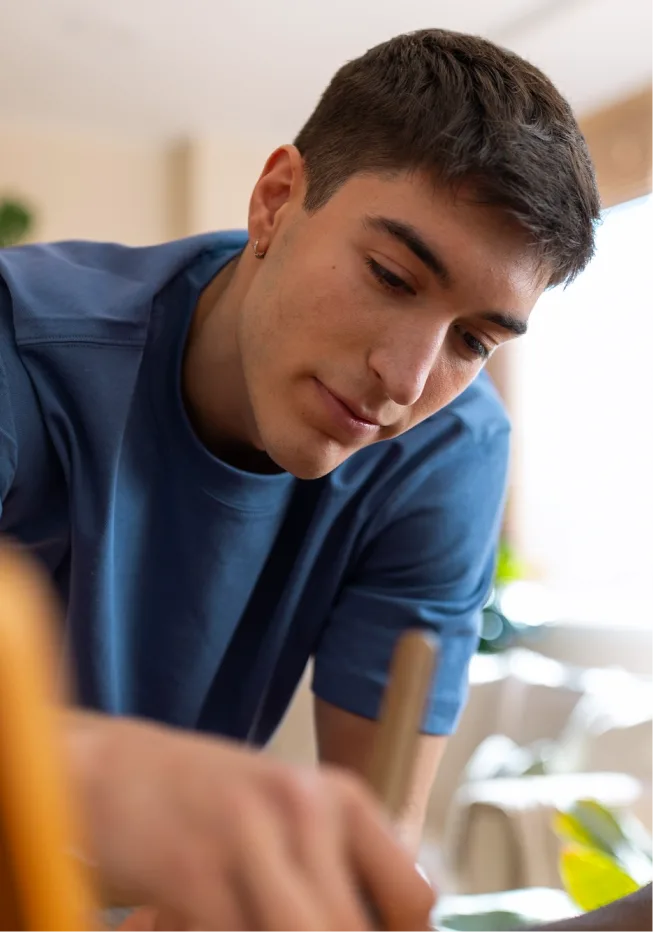 A young person writing down his emotions during a therapy session.