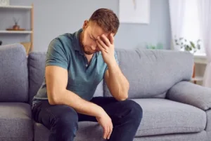 Man feeling overwhelmed while sitting on a couch, illustrating signs of feeling smothered in a relationship