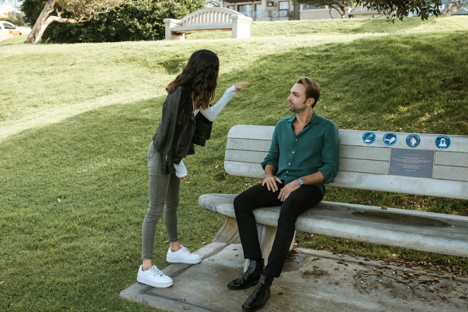 Woman confronting man in park as he sits on bench, symbolizing when to step back from a smothering relationship