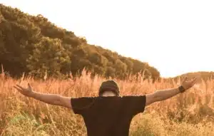 Man opening arms in the wild, emphasizing positive self-talk in therapy.