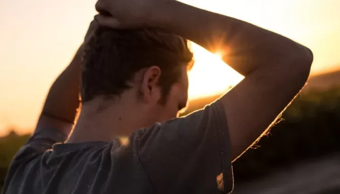 Man holding head on a sunny morning, illustrating stress in his life